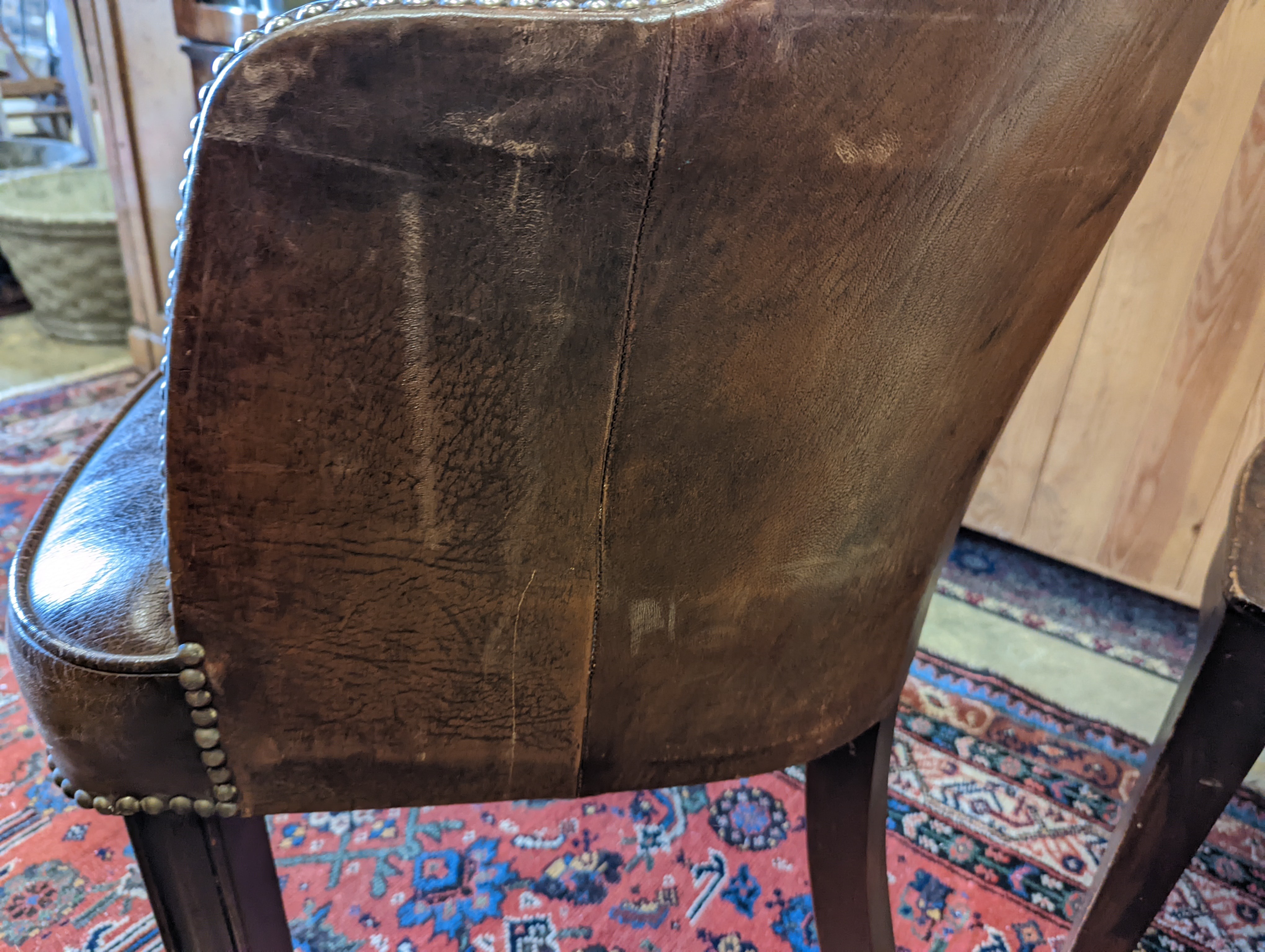 A brown leather upholstered desk chair, a mahogany hall chair and two upholstered armchairs